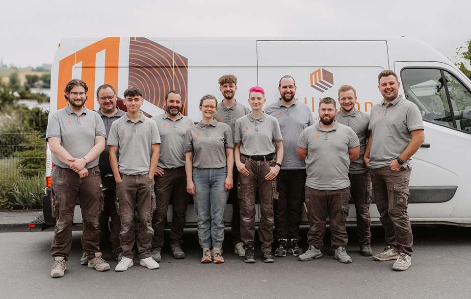Team vor Firmenwagen mit Logo im Freien